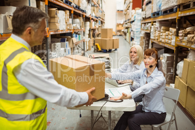 Manager wearing yellow vest giving box to his colleague