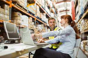 Warehouse worker and manager looking at laptop