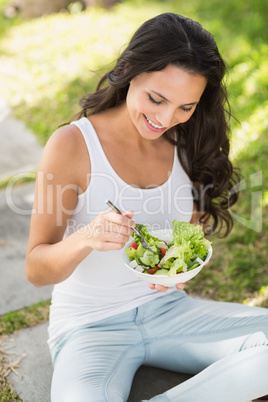 Pretty brunette eating bowl of salad