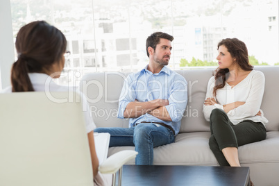 Unsmiling couple talking with their therapist