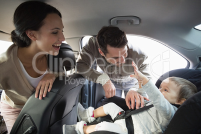 Parents securing baby in the car seat