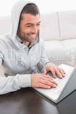 A smiling man using laptop at a table A smiling man using laptop at a table