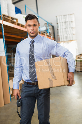 Warehouse manager holding cardboard box and scanner