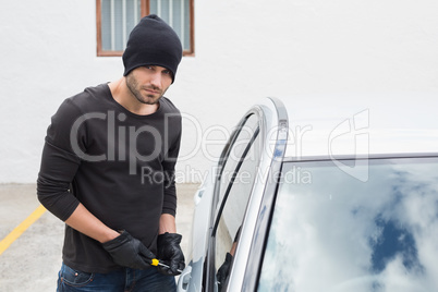 Thief breaking into car with screwdriver