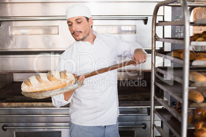 Happy baker taking out fresh loaf