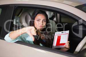 Woman gesturing thumbs down holding a learner driver sign