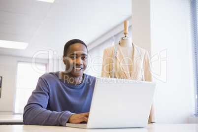 Smiling university student using laptop