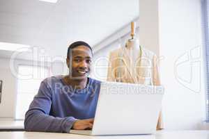Smiling university student using laptop
