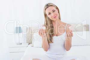 Smiling woman holding the pill and condom