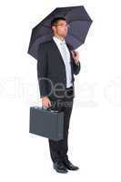 Businessman sheltering under bllack umbrella