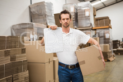 Delivery man with box and clipboard in warehouse