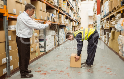 Manager watching worker carrying boxes