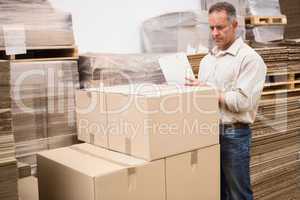 Warehouse worker checking his list on clipboard