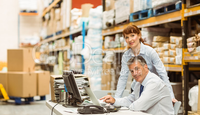 Warehouse managers working together on laptop