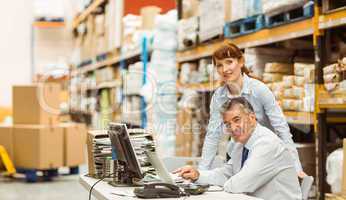 Warehouse managers working together on laptop