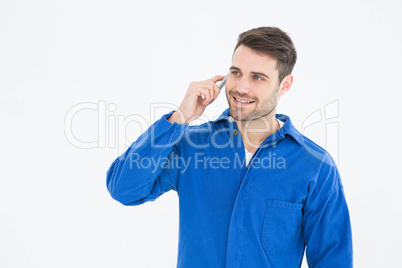 Happy young male mechanic using mobile phone