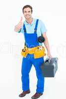 Plumber carrying tool box while gesturing thumbs up