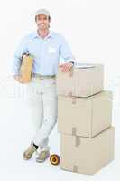 Handsome delivery man leaning on stacked cardboard boxes