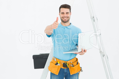 Construciton worker with laptop gesturing thumbs up