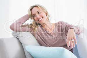 Blonde sitting on couch smiling and thinking