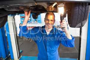 Mechanic using torch to look under car