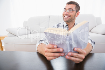 A smiling man reading a book