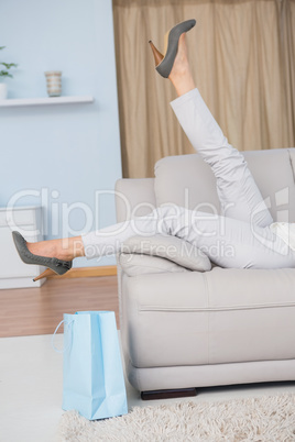 Legs of woman with heels lying on couch