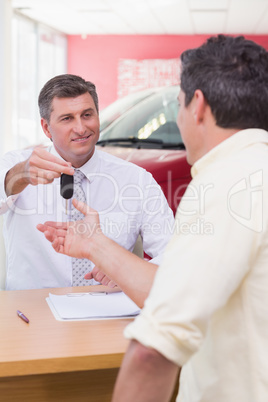 Smiling salesman giving a customer car keys