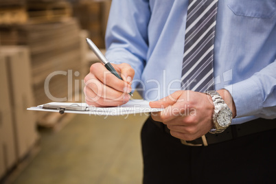 Warehouse worker checking his list on clipboard