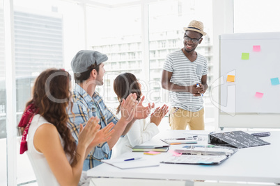 Smiling colleagues sitting and applauding businessman