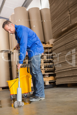 Focused man moping warehouse floor