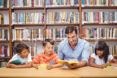 Cute pupils and teacher reading in library