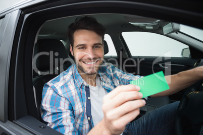 Young man smiling at camera showing card