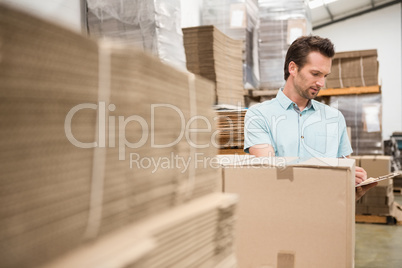 Warehouse worker checking his list on clipboard