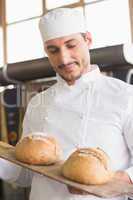 Baker showing tray of fresh bread