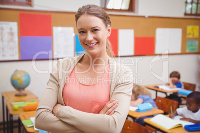 Pretty teacher smiling at camera with arms crossed