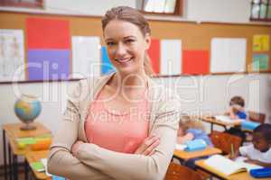 Pretty teacher smiling at camera with arms crossed