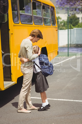 Mother hugging her daughter by school bus