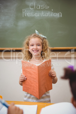 Cute pupil smiling at camera during class presentation