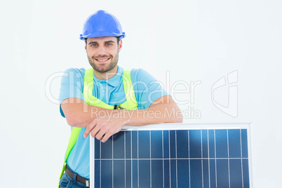 Happy worker leaning on solar panel