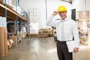 Warehouse manager wearing hard hat holding clipboard