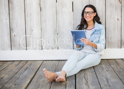 Pretty hipster sitting on ground with tablet