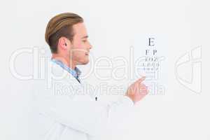 Optician in coat pointing eye test