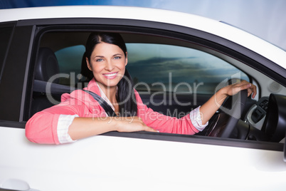 Smiling customer sitting at the wheel of a car for sale