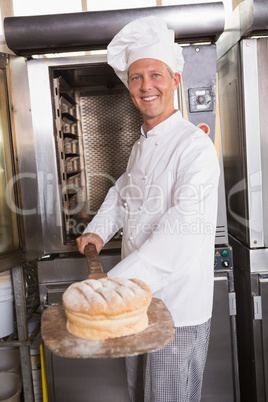 Happy baker taking out fresh loaf