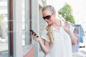 Pretty blonde texting and holding shopping bags