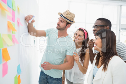 Man writing with marker and presenting at his colleagues