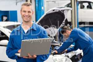 Smiling mechanic using a laptop