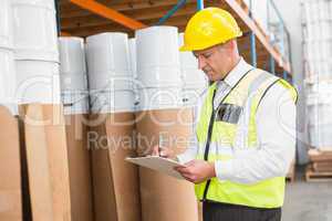 Warehouse manager checking his list on clipboard