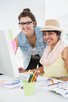 Smiling colleagues brainstorming and using computer